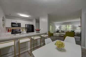 A white dining table with a vase of flowers on it.